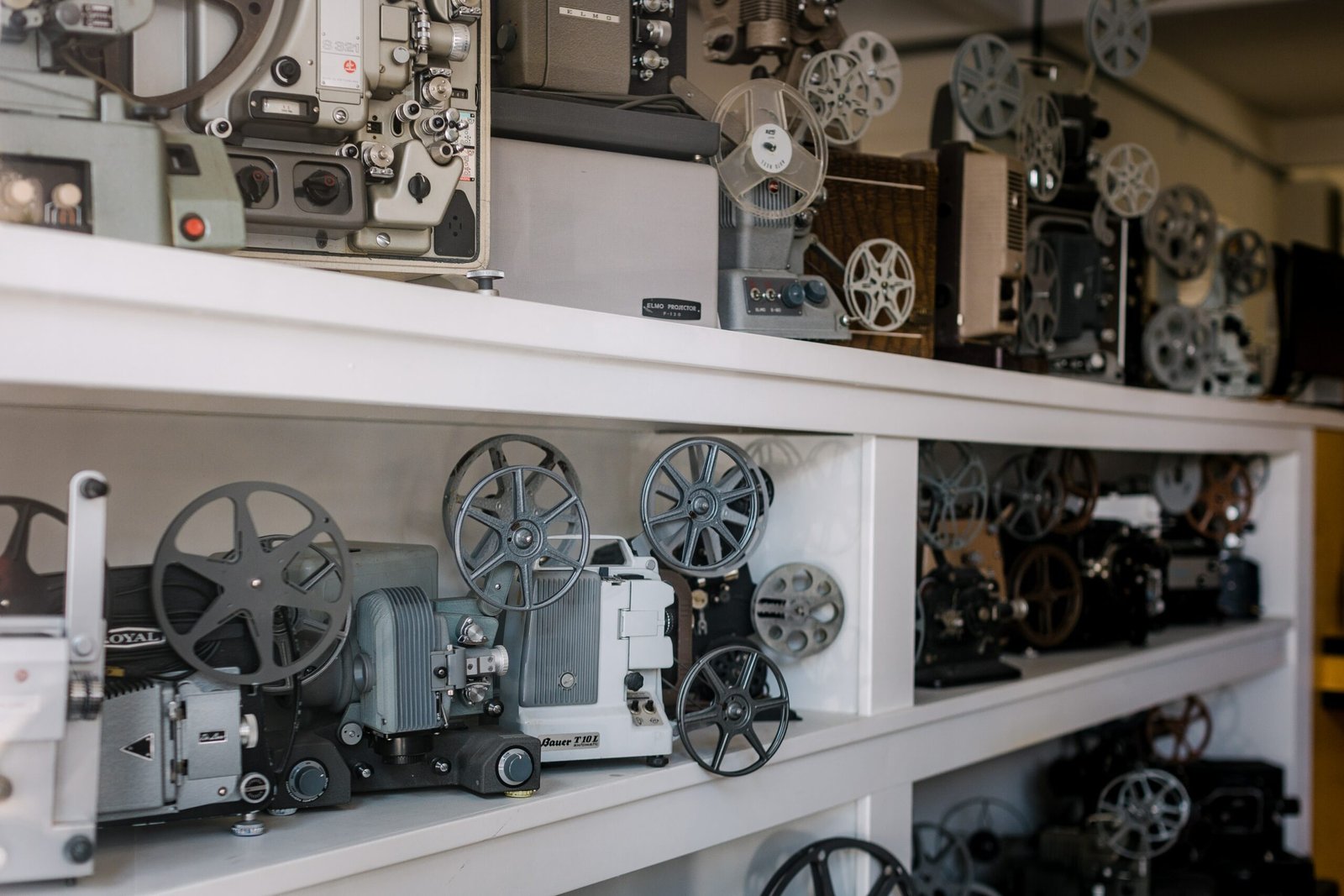 floor to ceiling white shelves hold vintage film projectors